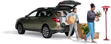 A mother and daughter unload plants and boxes from their SUV into their new home.